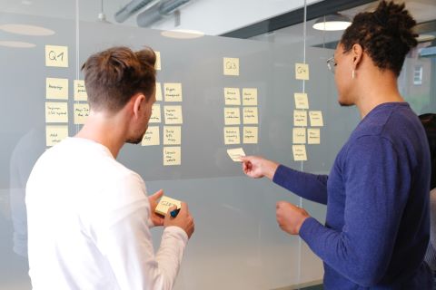 Two people posting sticky notes on a wall