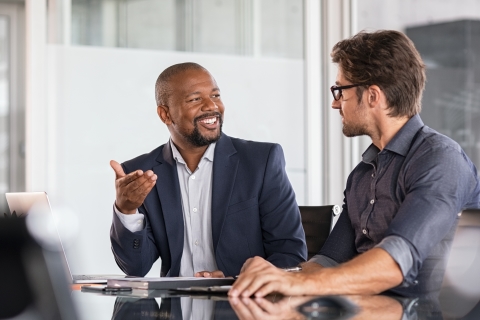 Two colleagues looking at each other, smiling and talking